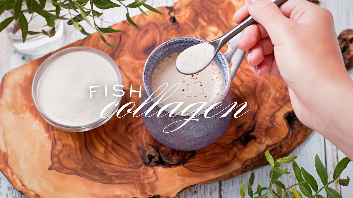 A hand scooping fish collagen powder into a mug of frothy drink on a rustic wooden board, with a bowl of collagen powder beside it. Text overlay reads 'Fish Collagen'.