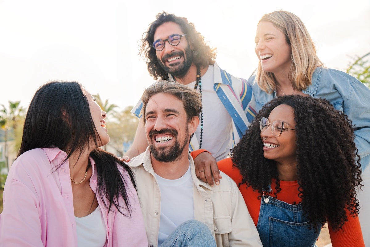 Group of young adult friends talking and having fun together on a social gathering outside.