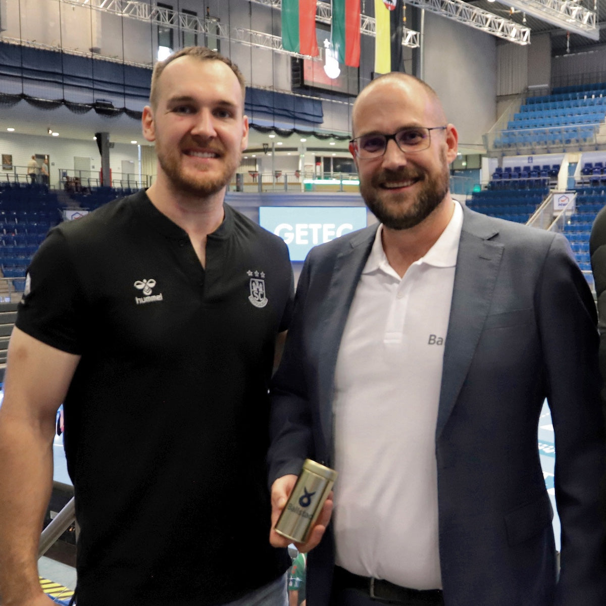 SC Magdeburg athlete and Ballstad representative at GETEC Arena holding Omega-3 supplement — sports partnership focused on performance and recovery