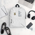 White backpack with the Ballstad logo and the acronym "POWER" (Pure, Original, Wild, Energetic, Resilient) displayed on a white surface, surrounded by black sneakers, a smartphone, wireless headphones, an open notebook with a pen, and a silver laptop.