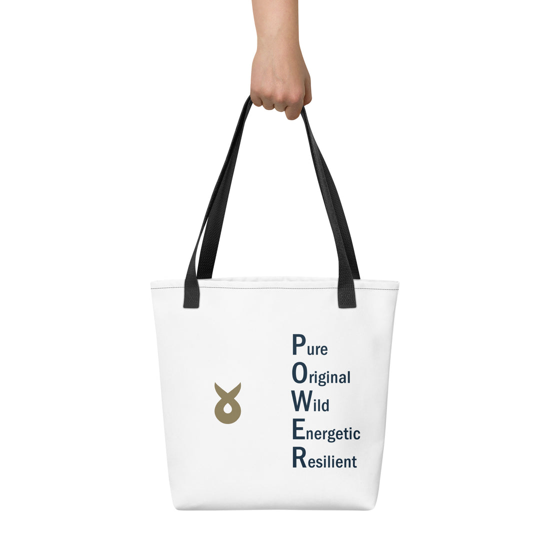 A white tote bag with black handles is held up by a hand against a white background. The bag features the Ballstad logo on the left side and the acronym “POWER” on the right side, spelled vertically with the words Pure, Original, Wild, Energetic, and Resilient.