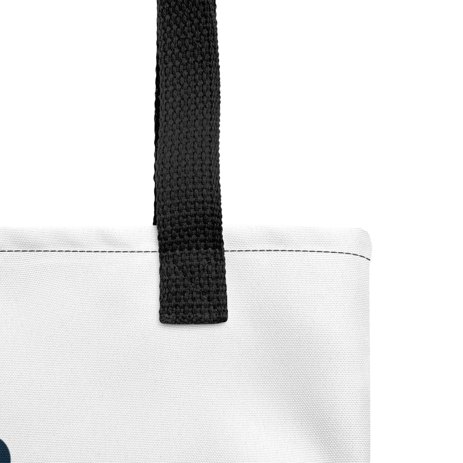 Close-up view of a white tote bag featuring a thick black strap attached with reinforced stitching. The bag has clean stitching details along the top edge and is made from a textured, durable fabric.