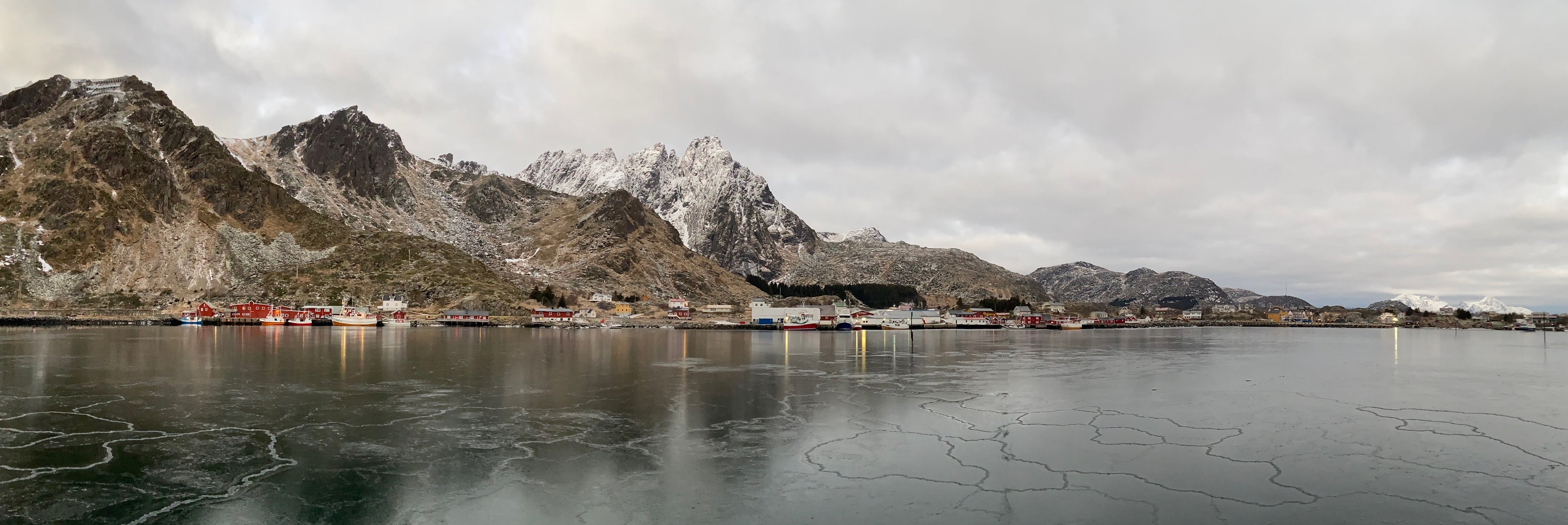 Harbor in Norway with snowy mountains in the background on a cloudy and cold weather