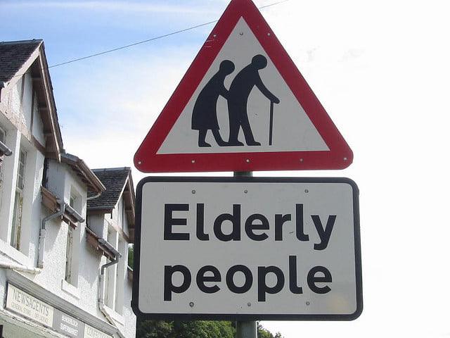 Traffic sign displaying elderly couple in a red triangle with "elderly people" writing below