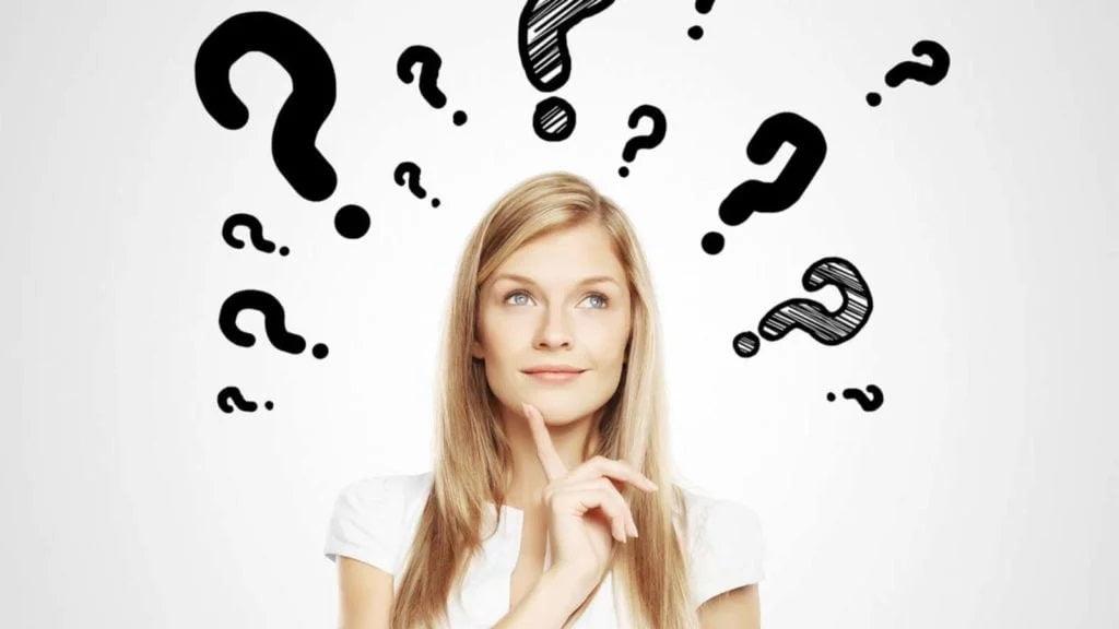 A thoughtful young woman with long blonde hair looking upward, surrounded by large black question marks on a white background, symbolizing confusion or decision-making.
