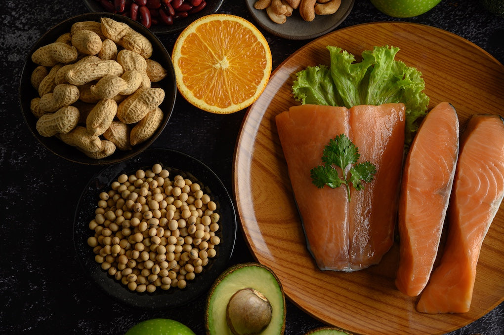  Legumes, fruits, greens and salmon pieces on a wooden plate.