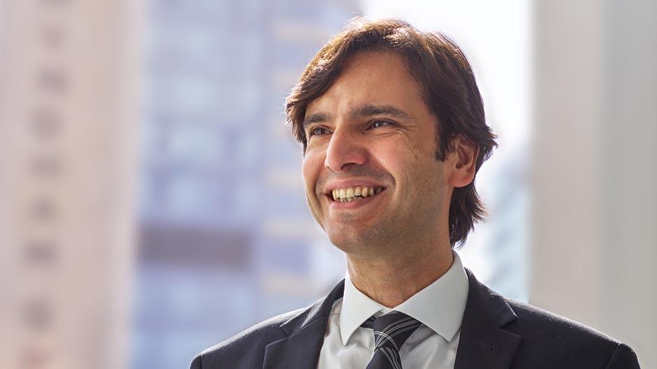 Smiling man with brown hair with a corporate background