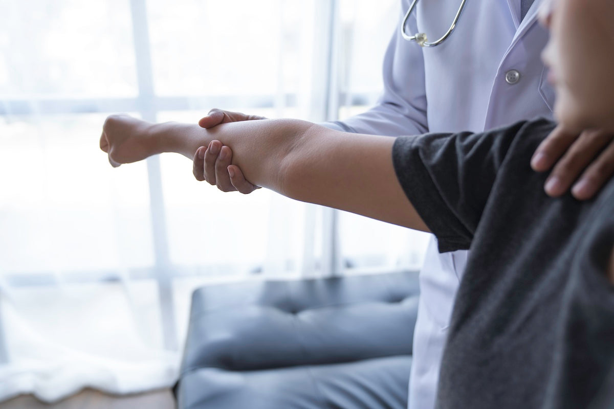A doctor examining a patient's elbow joint during a medical consultation, highlighting joint health and care.