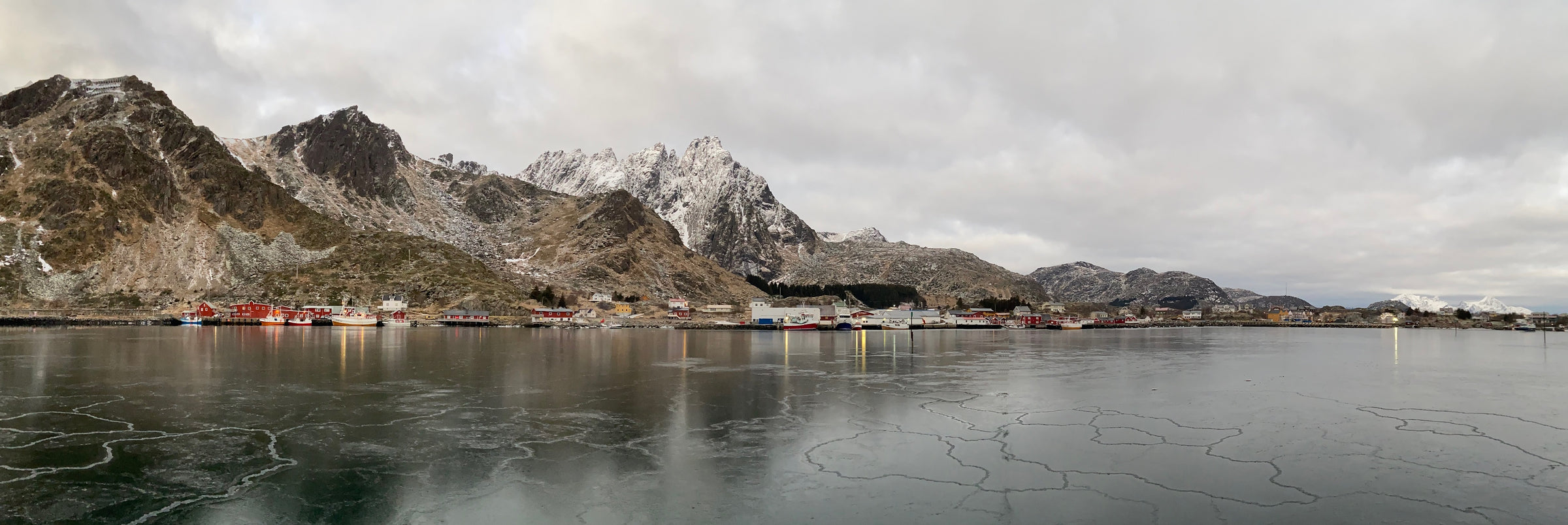 Harbor in Norway with snowy mountains in the background on a cloudy and cold weather
